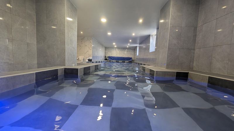 Das Hallenbad im Haus, beleuchtet, mit langem Becken